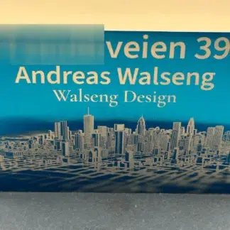 Lite postkasseskilt i blå aluminium med gravert skyline og adresse
