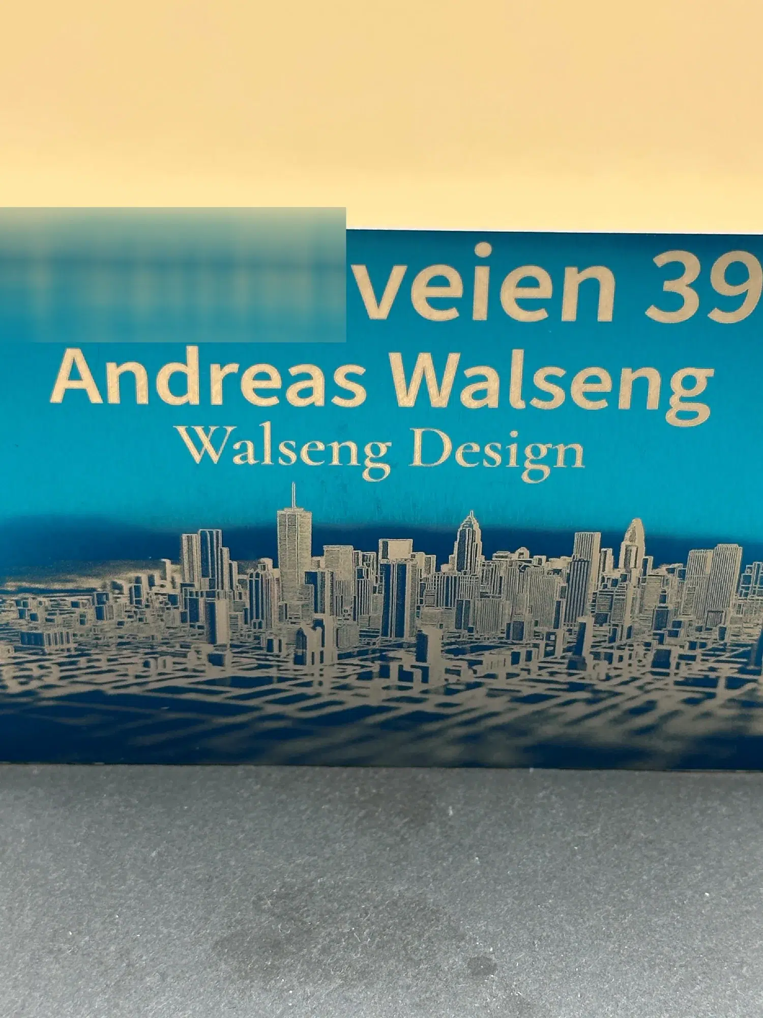 Lite postkasseskilt i blå aluminium med gravert skyline og adresse