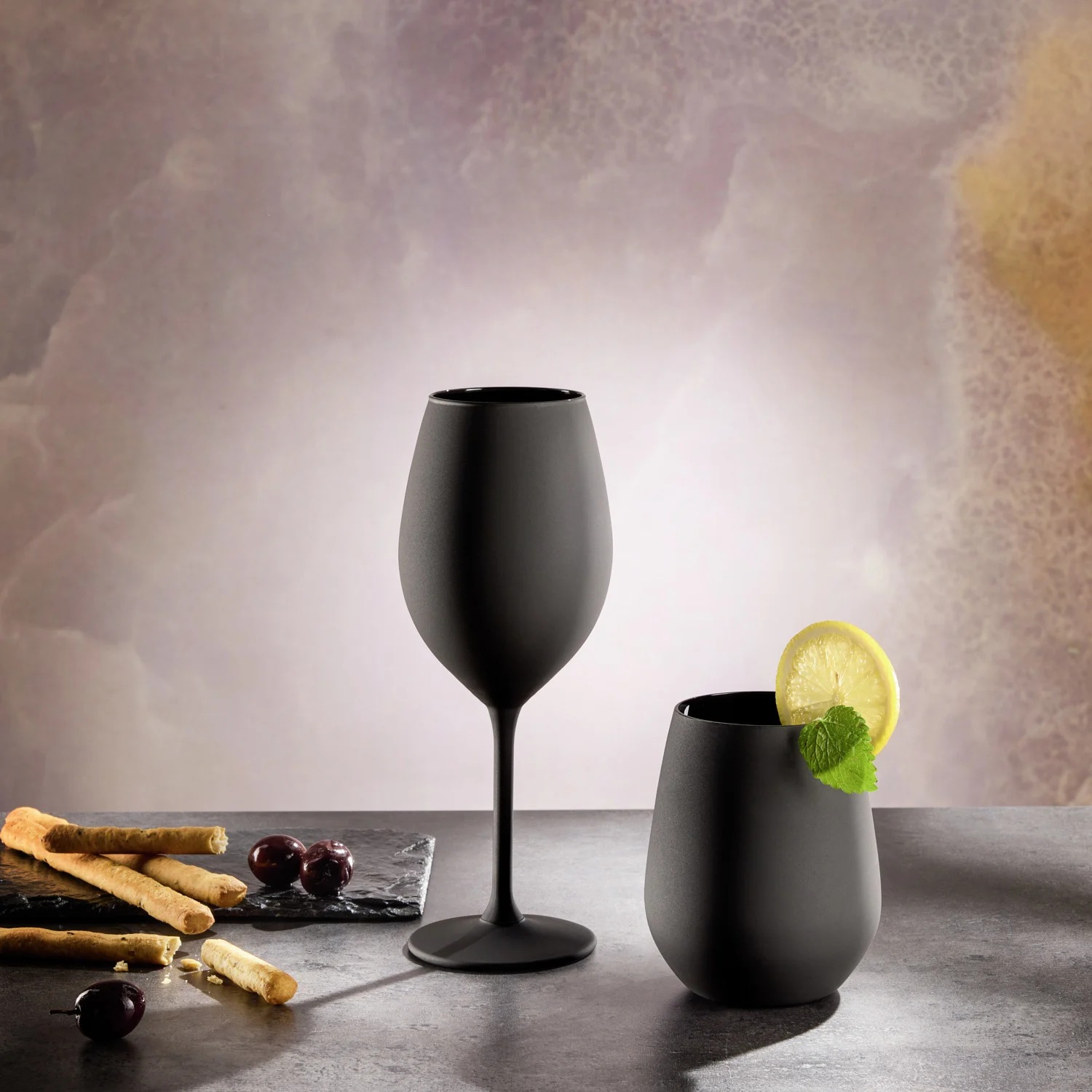 Kveld vinglass og Natt vannglass i matt svart på steinbord med oliven og grissini
